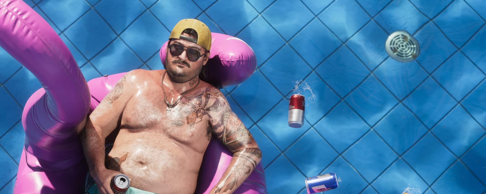 Mann mit Bierdose auf einem pinken Schwimmring in einem Pool